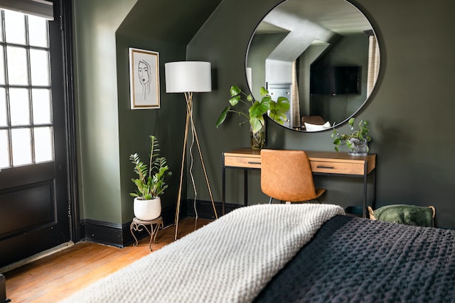dark green walls in a bedroom with a small wooden desk in the corner